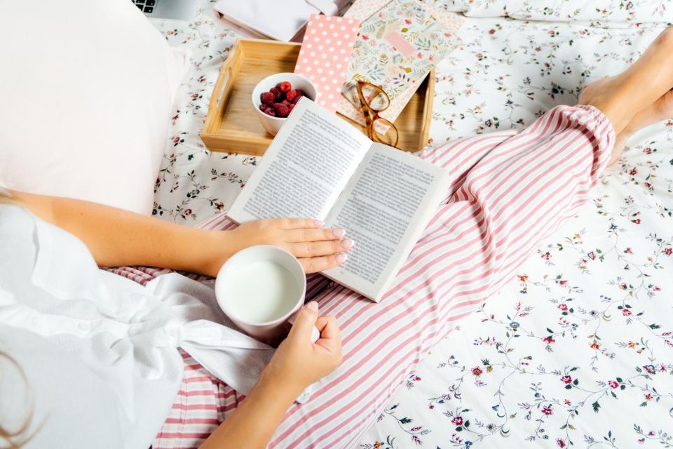 Femme lisant au lit avec un verre de lait.
