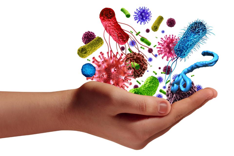 main humaine tenant des cellules microscopiques de virus et de bactéries cancéreuses comme métaphore de la maladie pathogène