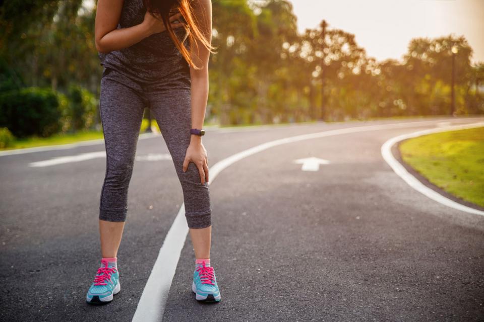 Jeune femme faisant son jogging, penchée en avant pour essayer de reprendre son souffle.