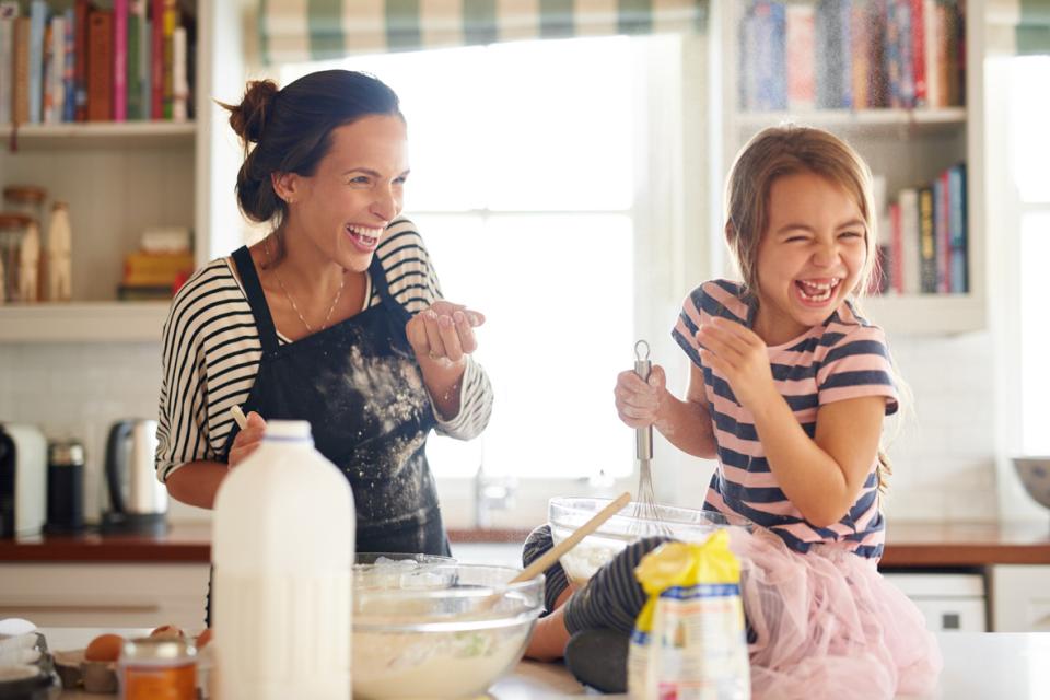 Mère et fille cuisinant et riant dans la cuisine avec un litre de lait sur le comptoir