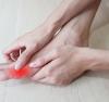 Une femme se frotte l'orteil avec un surlignage rouge de la zone enflammée
